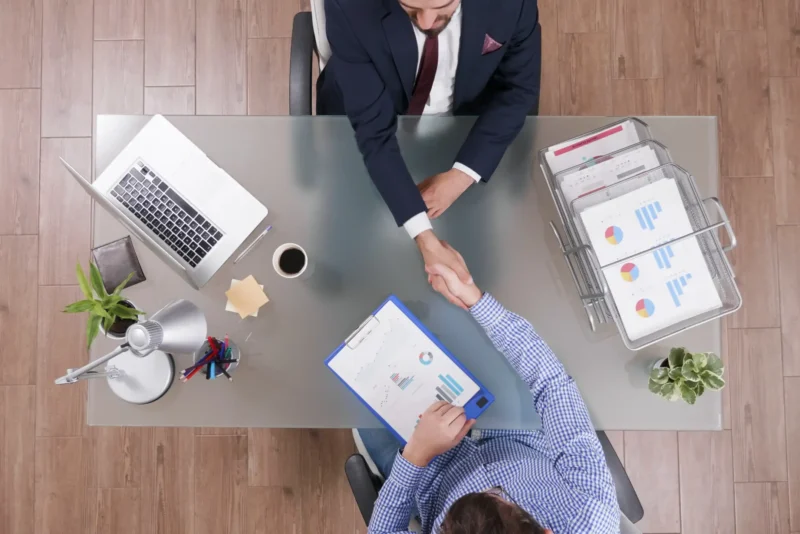top-view-businessmen-shaking-hands-business-negotiation-startup-office