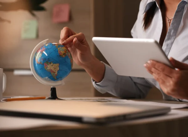 unrecognizable-businesswoman-using-digital-tablet-while-examining-globe-planning-her-vacation